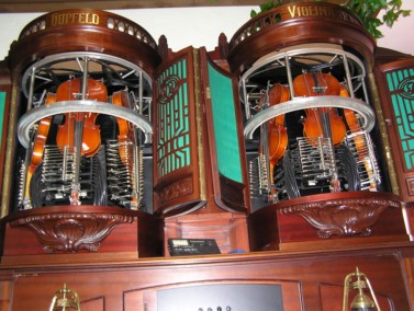 Hupfeld Violina, an automatic violin with piano. Instrument was marketed from around 1908, and despite its complexity, many were sold. The instrument on the left has three violins, each with a single string that is played by a rotating circular horse-hair bow. The instrument above has six violins.